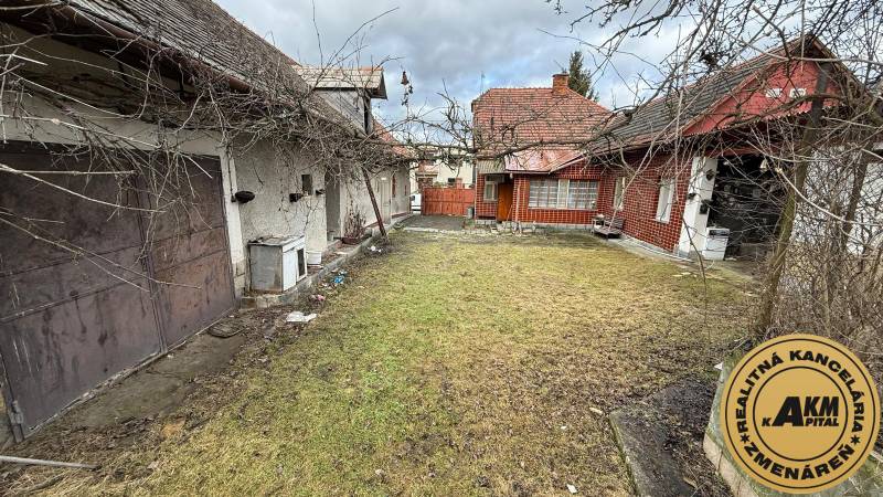 A family house in Babiná with a yard and a garage, visible older buildings and a fence.