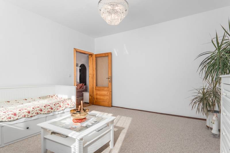 A bright room with floral bedding, a table, and a chandelier in a 4-room apartment.