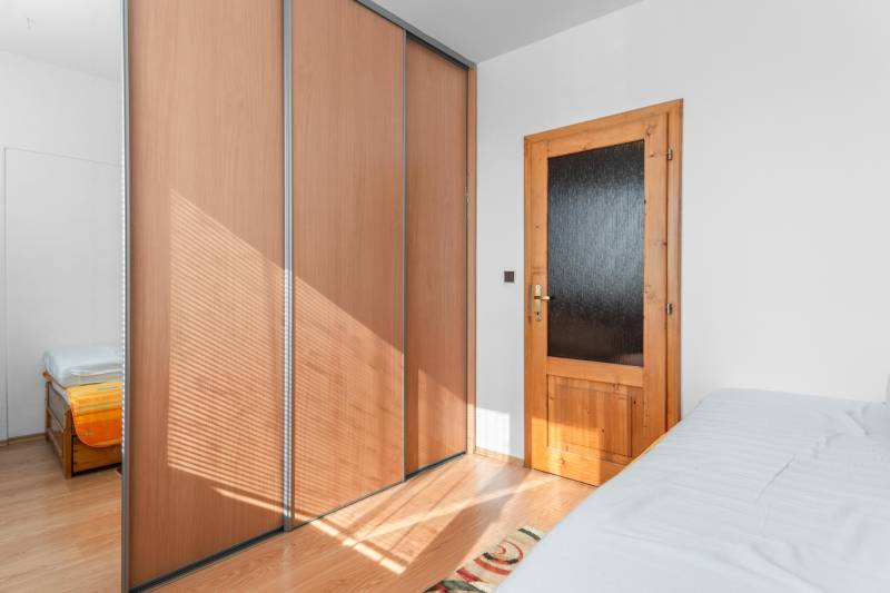 Bedroom with a wardrobe and wooden door in a 4-room apartment with a wood-decor floor.