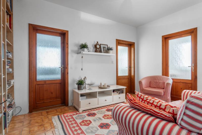 Living room in a 4-room apartment with red striped armchairs and a shelf on the wall.