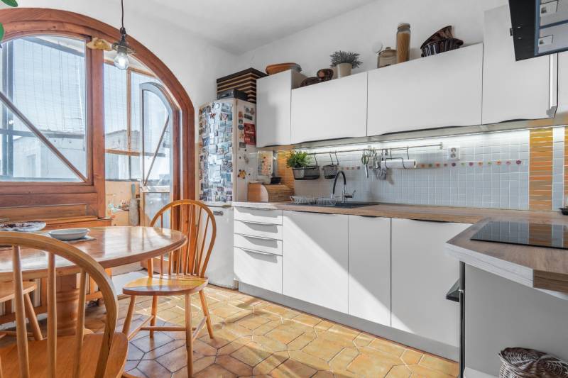 A kitchen in a 4-room apartment with wooden decor, an arched window, and a dining table.