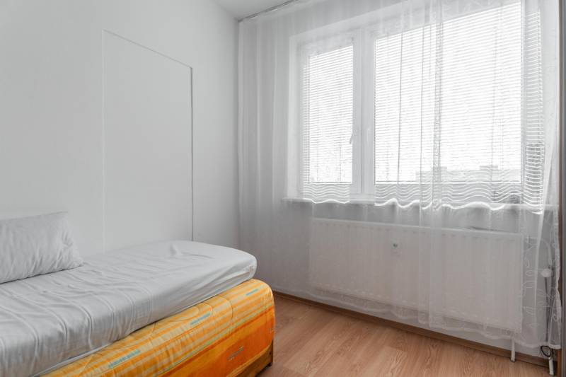 A bright room with a bed and a window with curtains in a 4-room apartment.