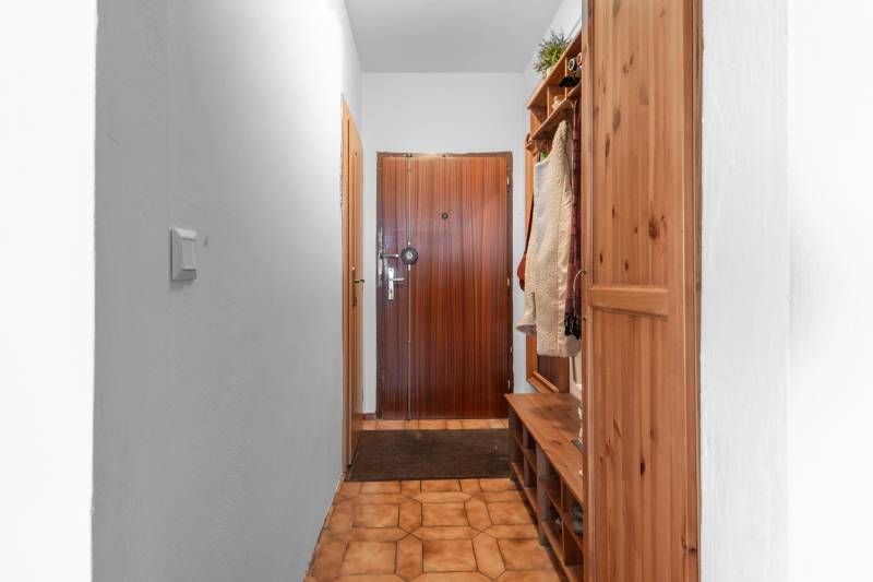 Entrance hallway in a 4-room apartment with wooden furniture and tiled floor.