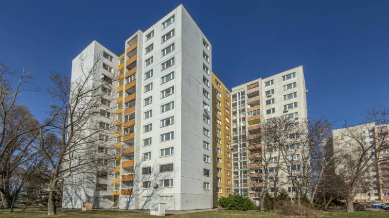 A high-rise building with balconies on Ševčenkova Street in Bratislava, Petržalka, surrounded by trees.