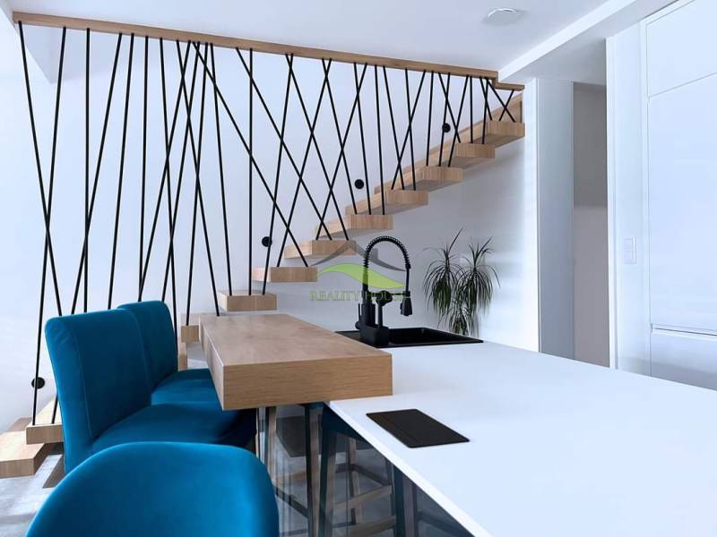 The interior of a family house with a staircase, blue chairs, and a kitchen counter.