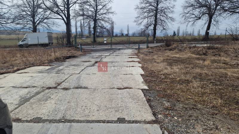 Area with a paved road and gate on Východná Street in Poprad, warehouses and halls.