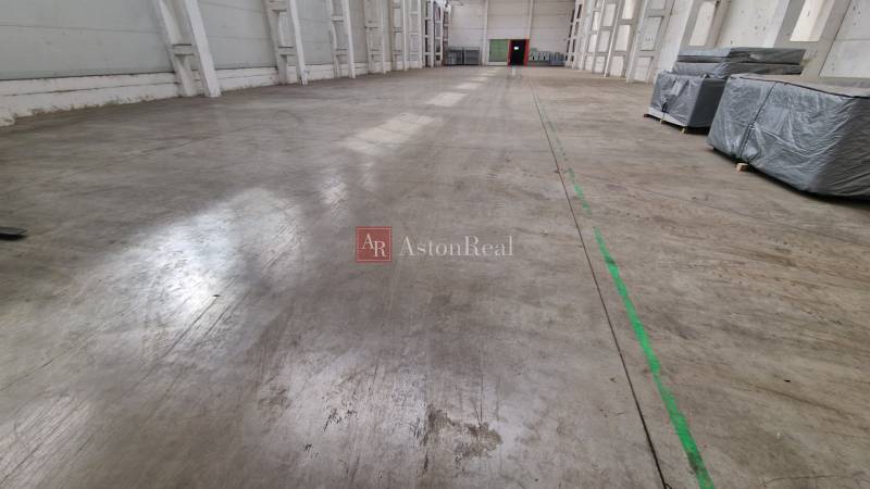 Spacious interior of warehouses and halls with concrete floor and packages on the left side.