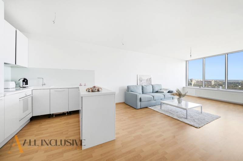 A cozy kitchen with white cabinets, a sofa, and a large glass wall in a 2-room apartment.