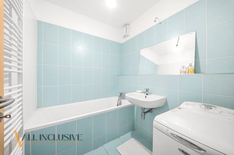Bathroom in a 2-room apartment with blue tiles, a bathtub, and a washing machine.