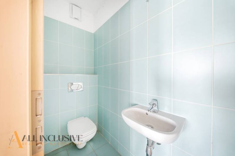 Bathroom with blue tiles and a wall-hung toilet in a 2-room apartment.