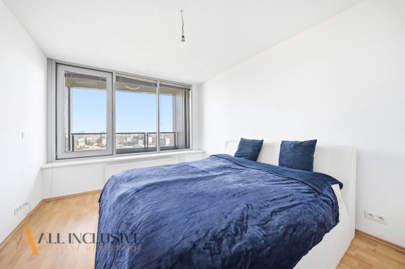 Bedroom in a 2-room apartment with a bed and a large window, floor with wooden decor.