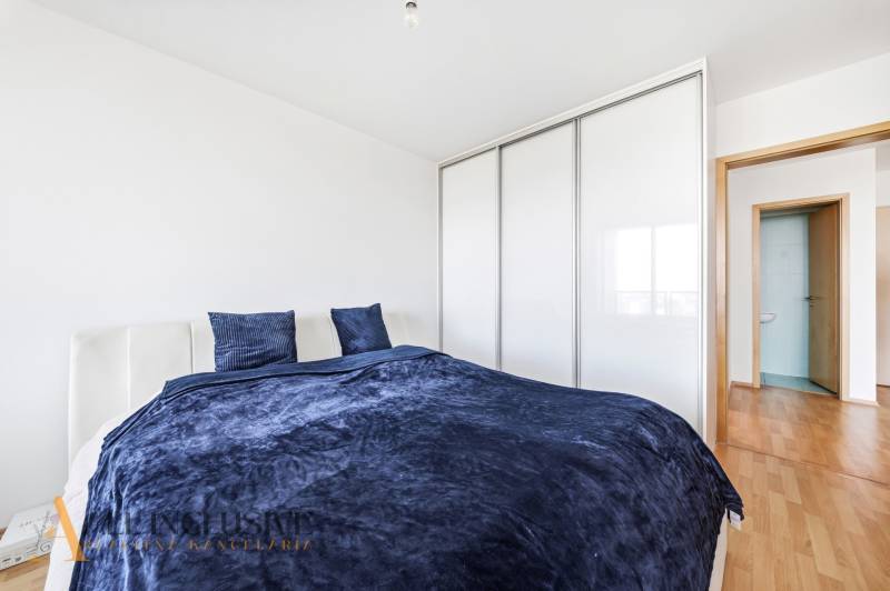 A bedroom in a two-room apartment with a bed, wardrobe, and floor with a wooden decor.