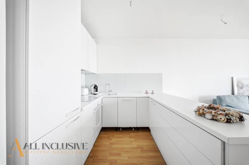 White kitchen in a 2-room apartment with wood-patterned flooring and appliances.