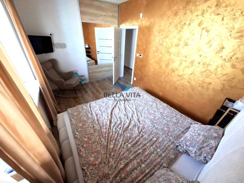 A bedroom in a family house with a wood-patterned floor, brown curtains, and a patterned bed.