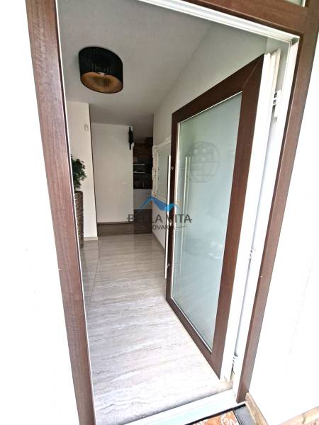 Entrance to a family house with large glass doors and a floor with a wooden decor.