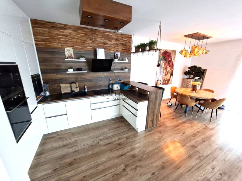 A kitchen in a family house with a wooden decor floor, a dining table, and decorative lights.