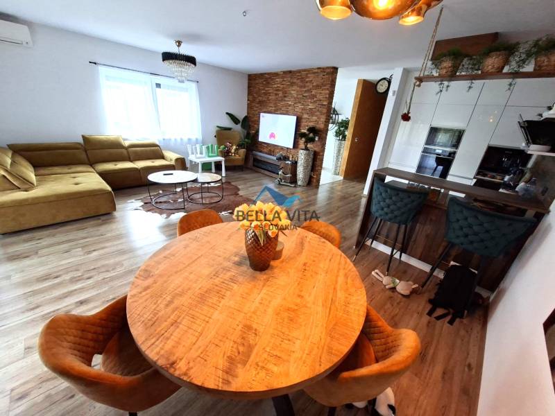 Living room in a family house with a sofa, dining table, and wooden decor flooring.