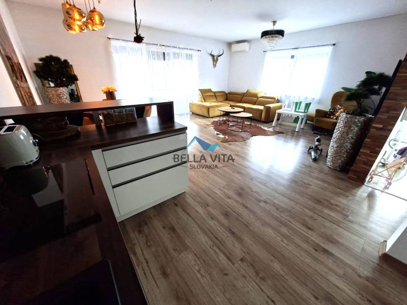 Living room in a family house with a wooden decor floor and a light-colored sofa.