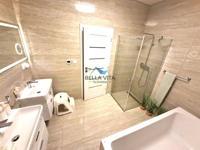 A bathroom in a family house with a bathtub, shower, and double sink.
