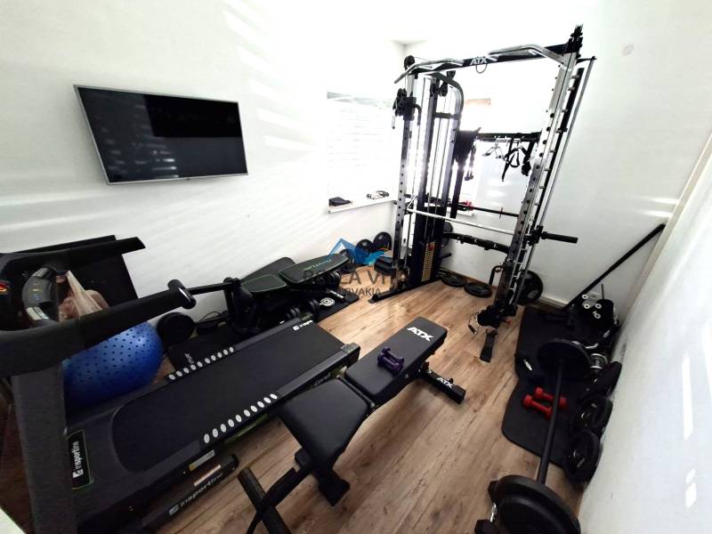Home gym with various exercise machines and a wooden decor floor.