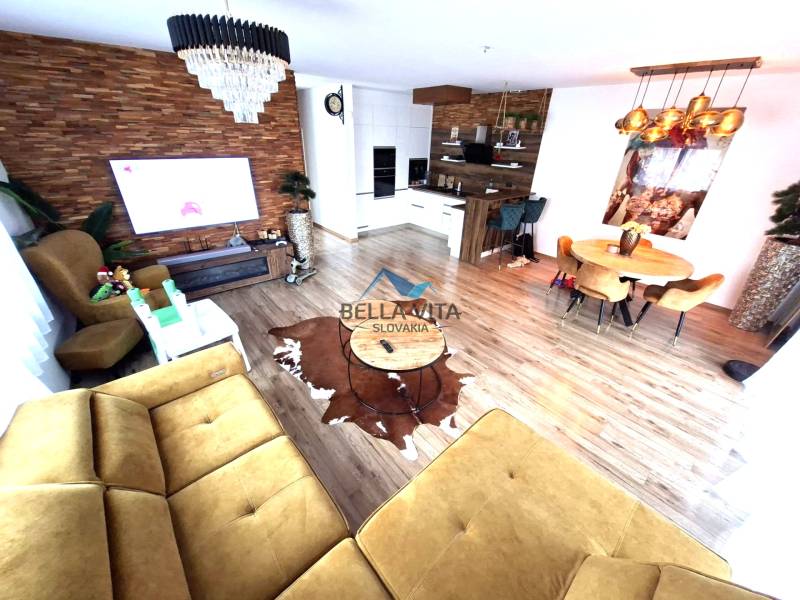 Living room with a sofa, dining table, and wooden decor flooring in a family house.