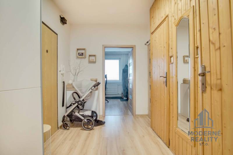 A hallway with light wood decor and a stroller in a 3-room apartment.