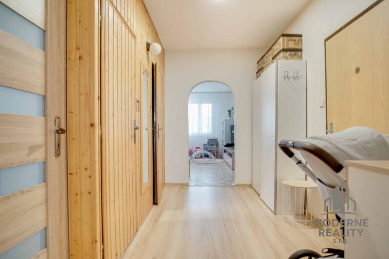 A hallway in a 3-room apartment with a wooden decor floor, with a wardrobe and doors.