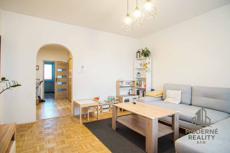 Living room in a three-room apartment with a wooden decor floor and light furniture.