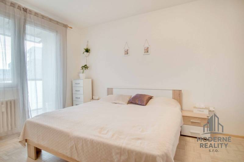 A bright bedroom in a 3-room apartment with white furniture and a bed.
