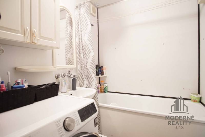 The bathroom in the 3-room apartment includes a bathtub, a washing machine, and storage spaces.