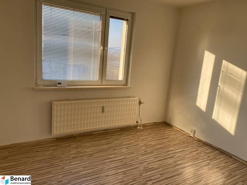 A room with a window, blinds, a radiator, and a floor with a wooden decor in a 3-room apartment.