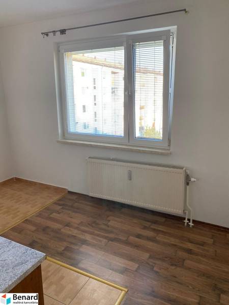 White wall, window with blinds, floor with wood decor, radiator in a 3-room apartment.