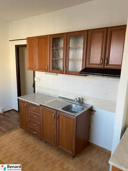 A kitchen in a 3-room apartment with wooden cabinets and tiles, floor with wooden decor.