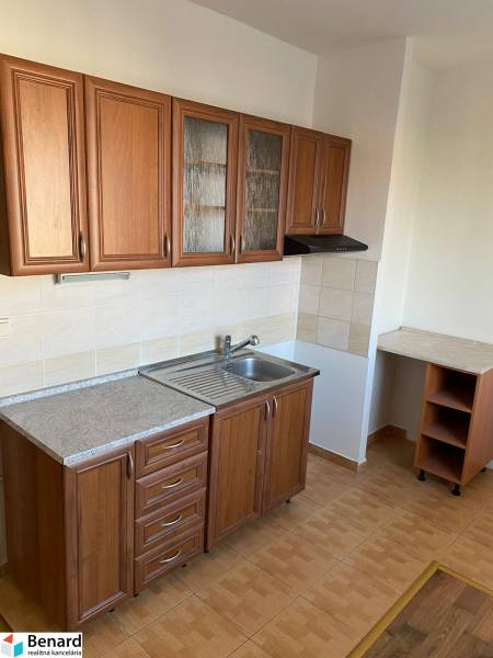 A kitchen with wooden cabinets and a sink in a 3-room apartment, flooring with a wooden decor.