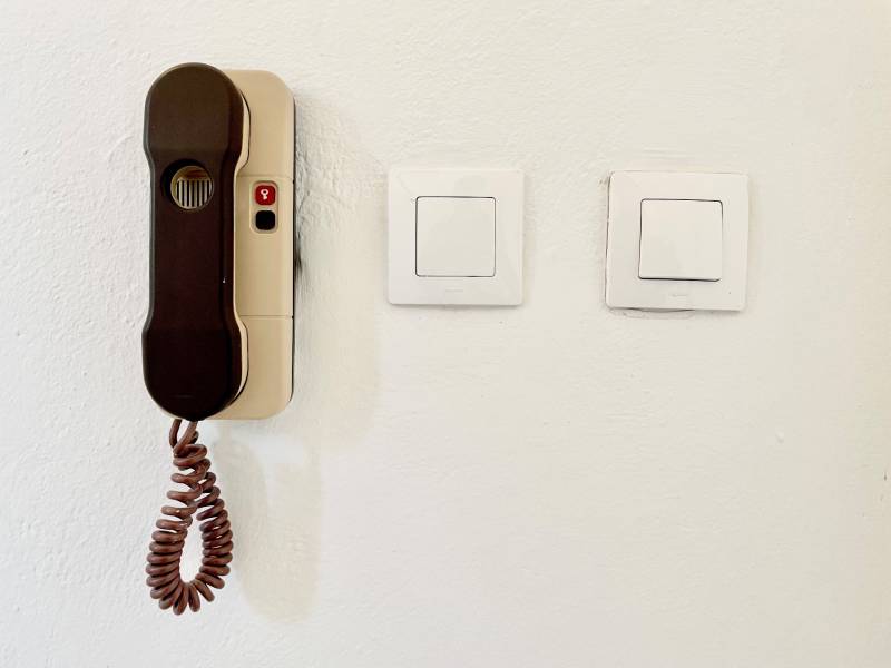 A wall with two switches and an intercom in a studio apartment.