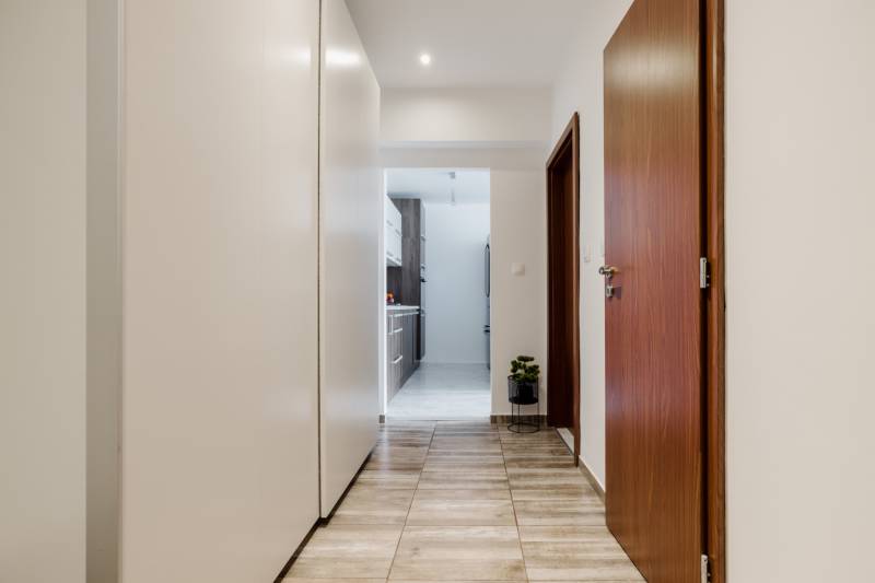 A hallway in a 2-room apartment with a wooden decor floor, a wardrobe, and fixed lighting.