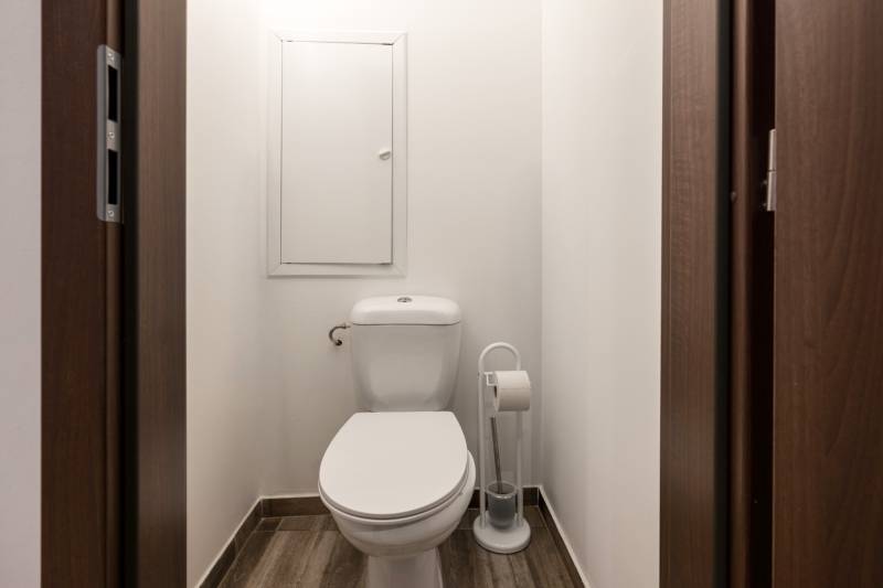 A toilet with a wooden decor floor in a 2-room apartment.