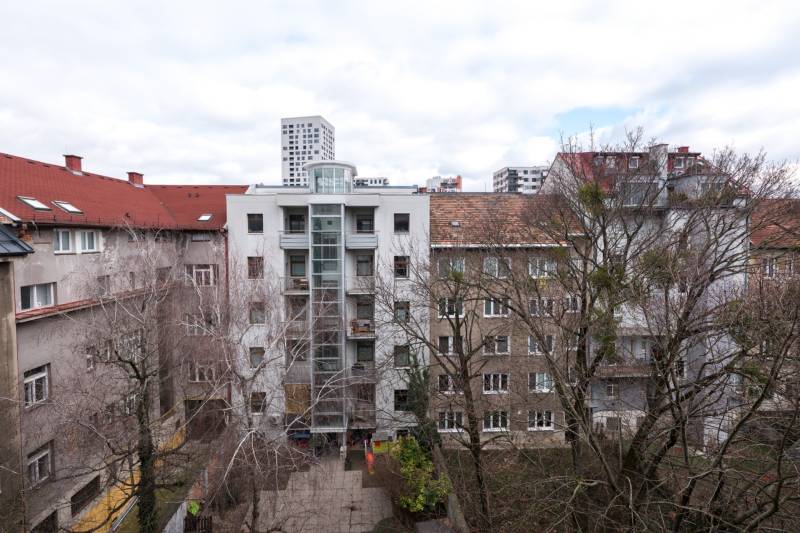 View of apartment buildings in Bratislava - Ružinov with front gardens and trees.