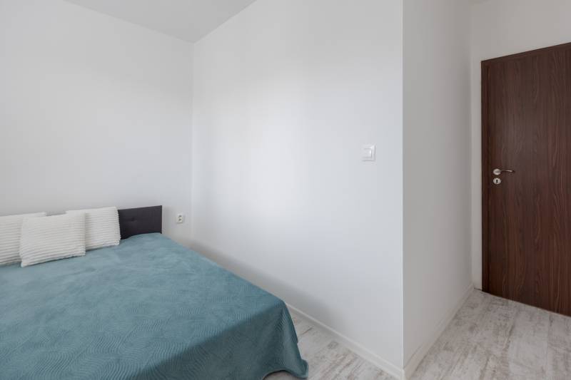 Bedroom in a 2-room apartment with a bed, pillows, and wooden doors.