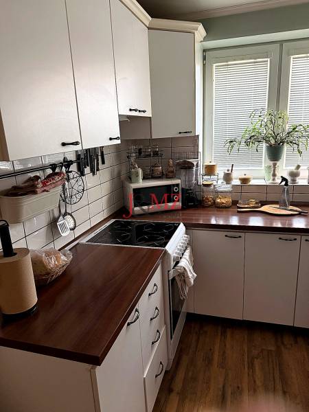 A kitchen in a 2-room apartment with white cabinets and a wood-patterned floor.