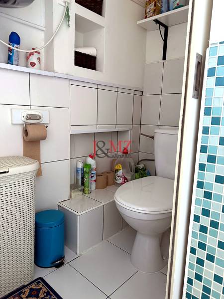 Bathroom in a 2-room apartment with white tiles, storage spaces, and a toilet.