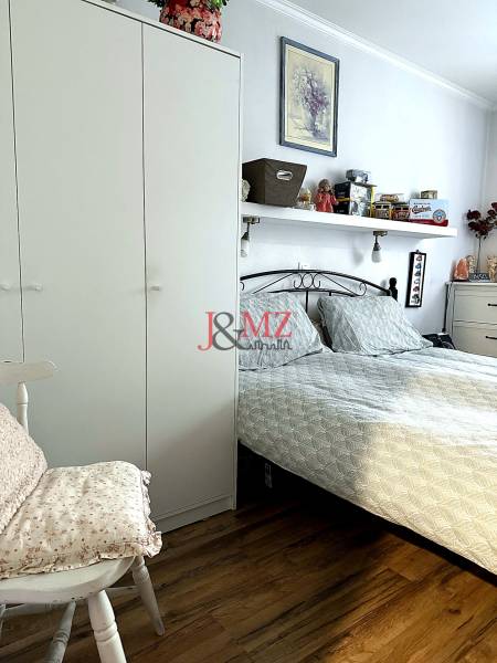 A bedroom in a 2-room apartment with a bed, a wardrobe, and a floor with a wooden decor.