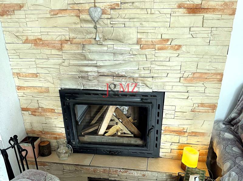 Fireplace in a 2-room apartment with artificial stone cladding and a decorative heart.