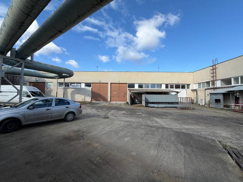 Warehouses and halls in Nové Zámky on the street Nové Zámky with an industrial complex and cars.