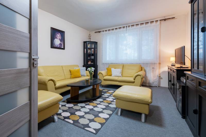Living room with yellow sofas, a painting on the wall, and a patterned carpet in a 4-room apartment.