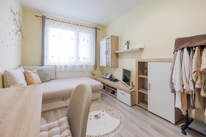 A bright room with a bed, a desk, and a wardrobe in a 4-room apartment.