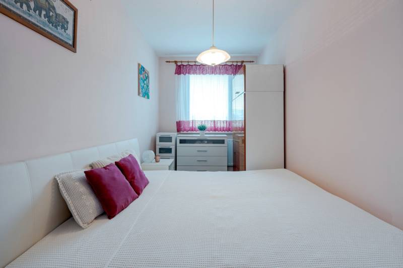 A bedroom with light furniture and decorative pillows in a 4-room apartment.