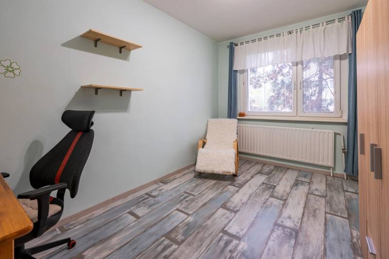 A room with a chair, shelves, and a floor with a wood decor in a 4-room apartment.
