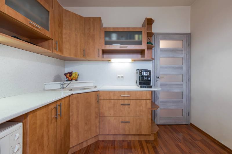 A kitchen with cabinets and a wooden decor floor in a 4-room apartment.