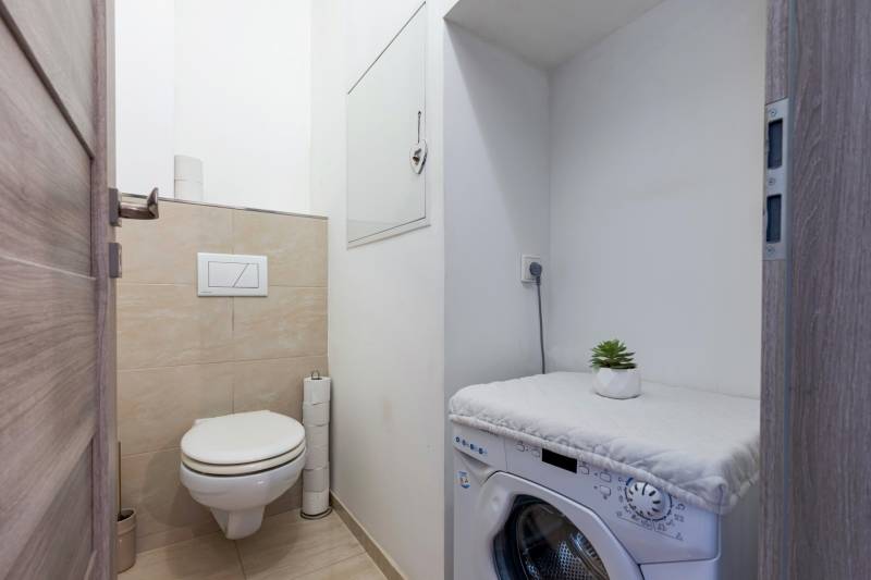 Bathroom with a toilet and a washing machine in a 4-room apartment, simple and practical.
